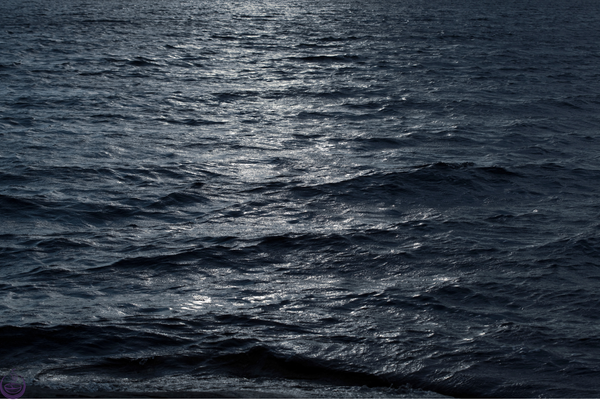 Moonlight glinting across dark rippled water at night