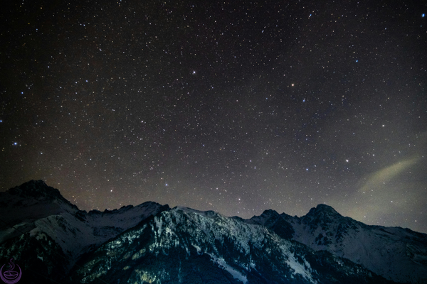Starry night sky above snow-dusted mountains