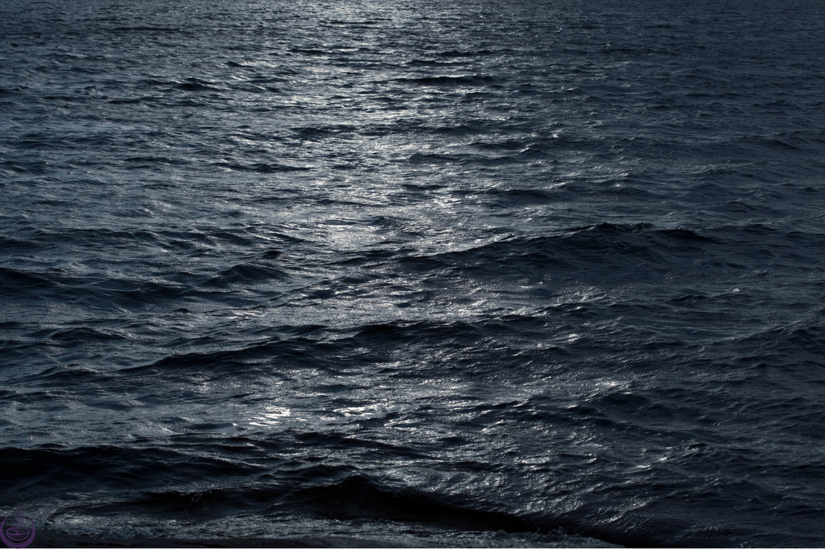 Moonlight glinting across dark rippled water at night