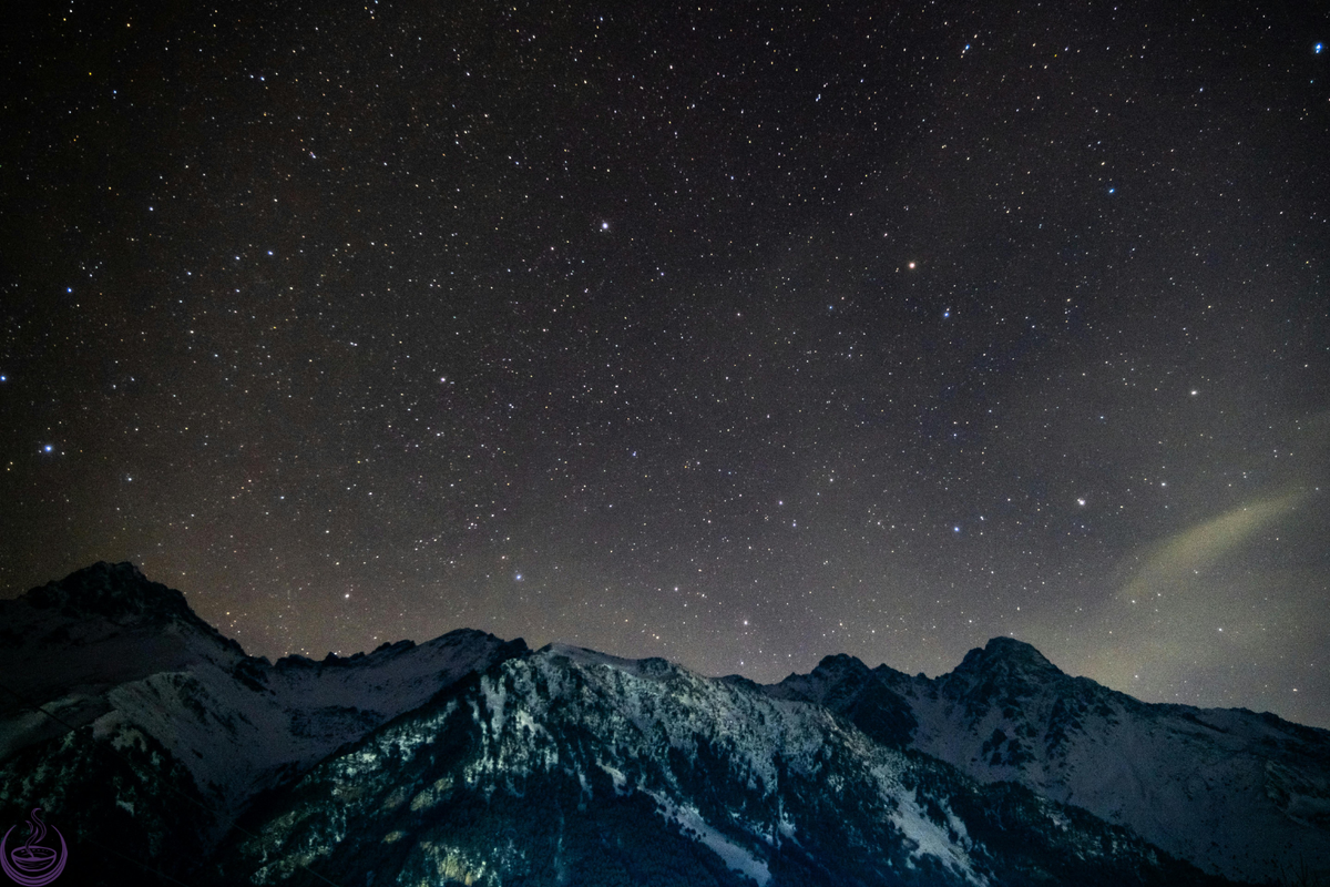 Starry night sky above snow-dusted mountains