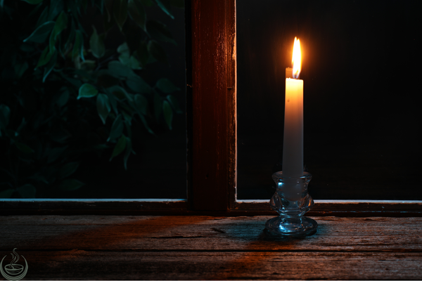 A single lit candle on a wooden table in a dark room