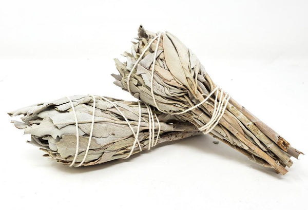 A tied bundle of dried silvery-green White Sage leaves resting on a neutral surface