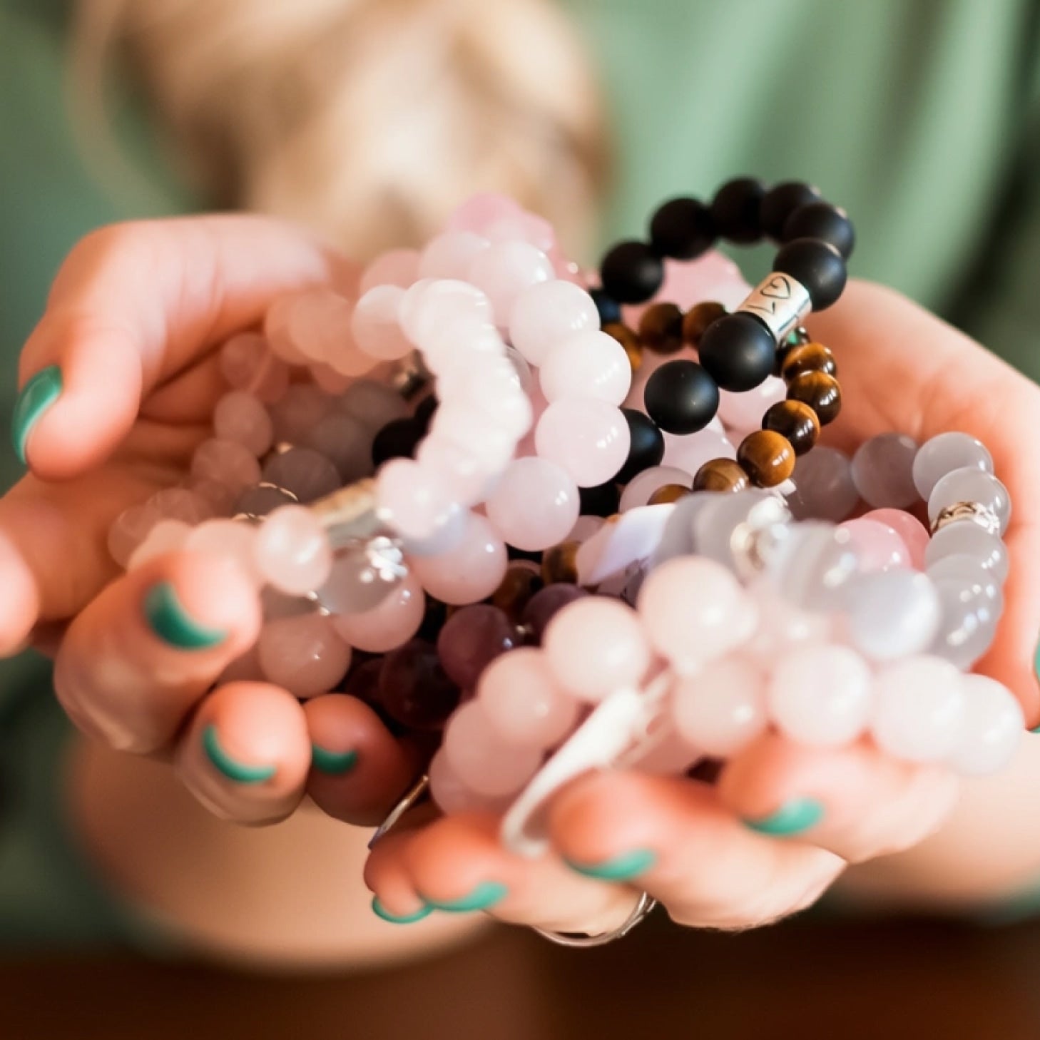 A digital photograph features a beaded stretch bracelet arranged in a circle, alternating rose quartz, amethyst, and labradorite beads, set against a neutral beige background.
