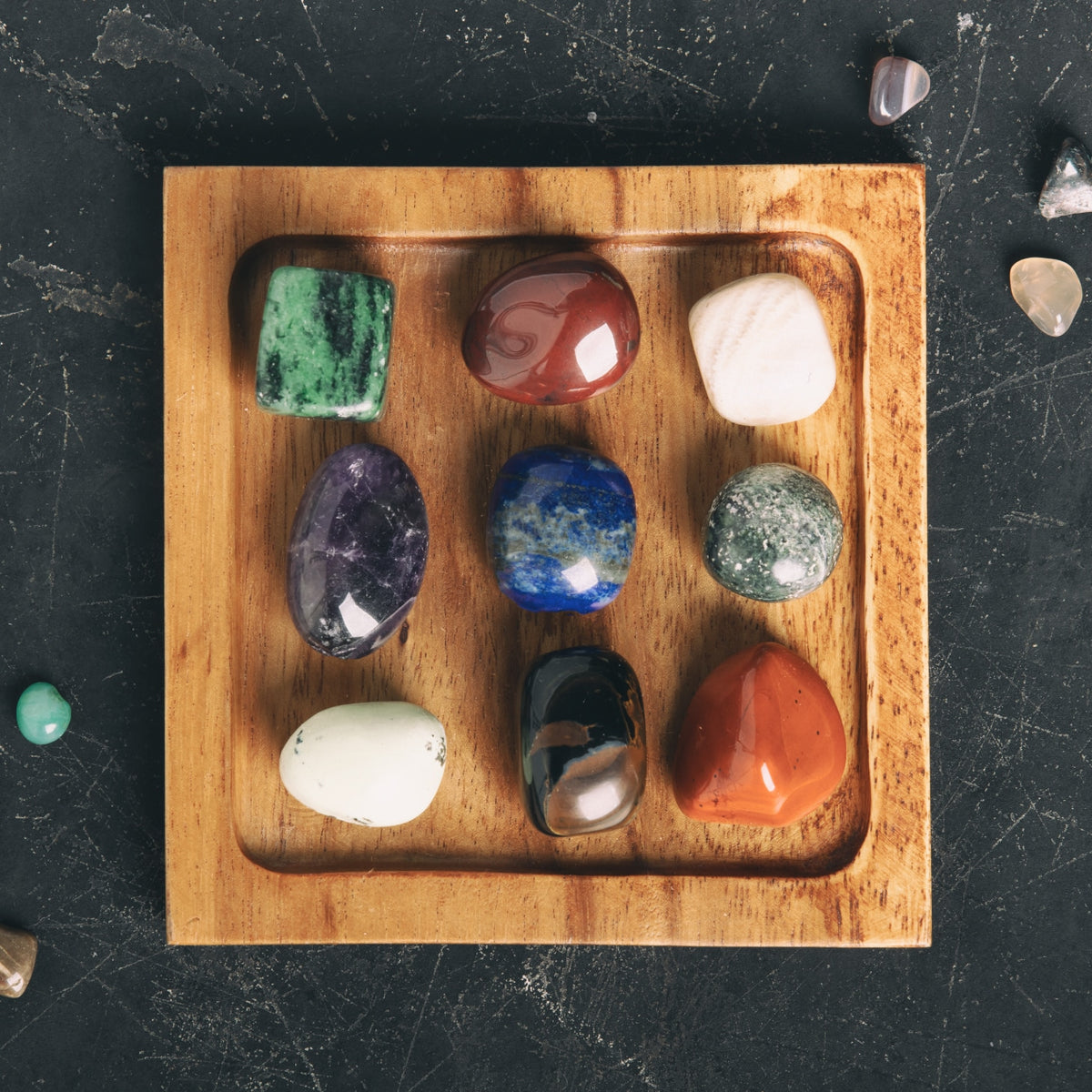 Set of colorful crystals on a wooden tray with a dark background