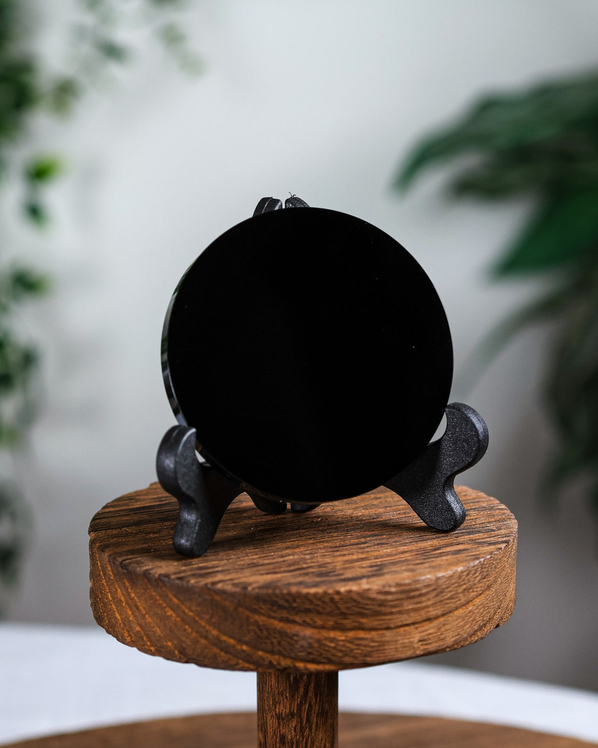 Black obsidian scrying mirror on its stand on a round wooden table