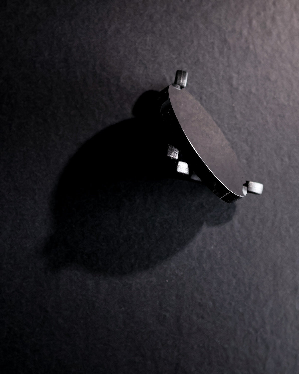 Back of the obsidian scrying mirror and its stand on a dark surface