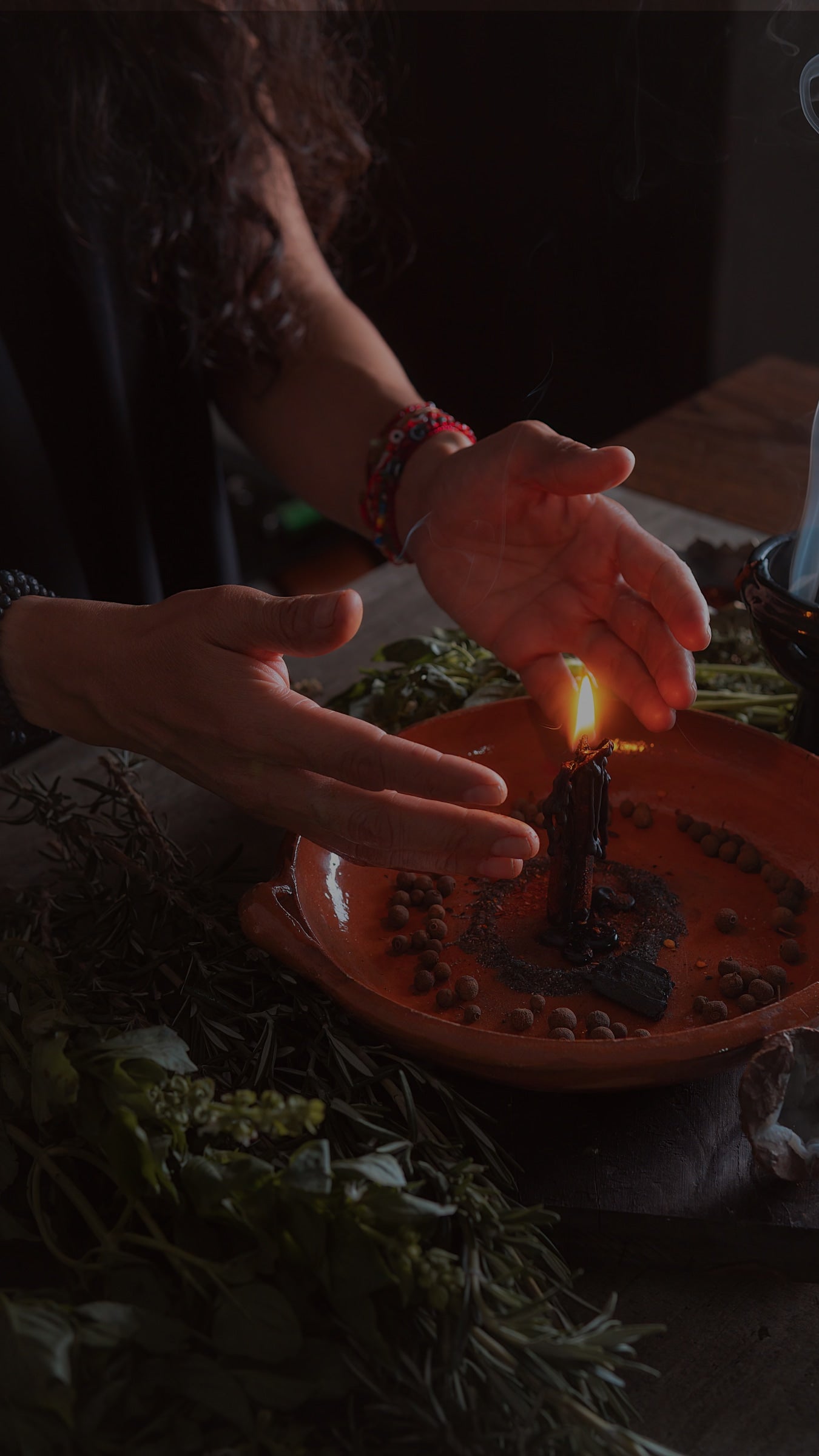 Person lighting a candle in a traditional setting with hands and a candle visible.