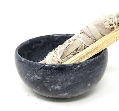 Black marble bowl with a sage bundle and palo santo